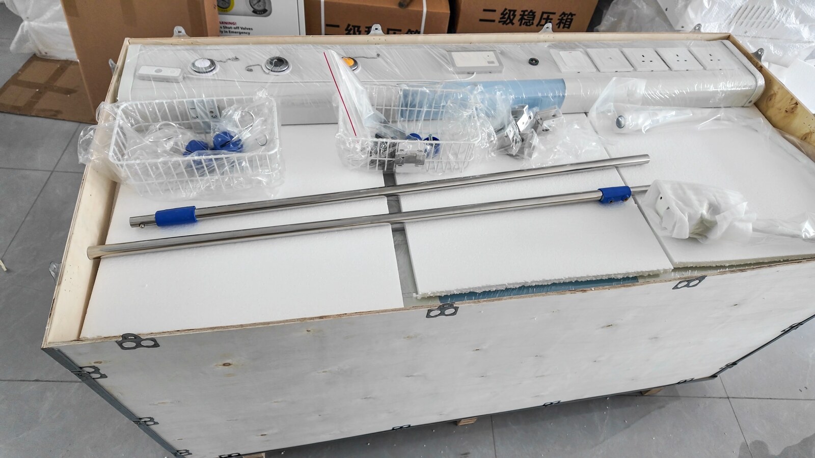 A wrapped bed head unit and accessories inside a foam-lined wooden crate.